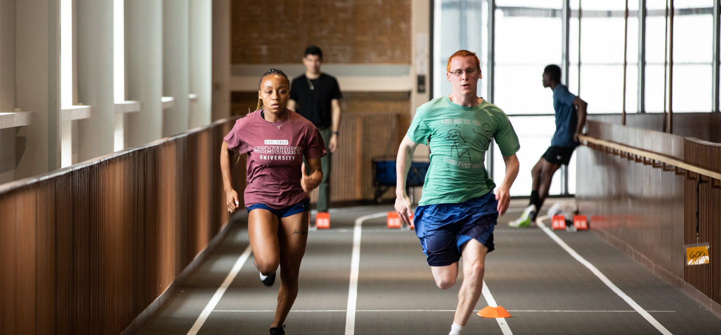 Two students run down the track at the Powerhouse in an race.