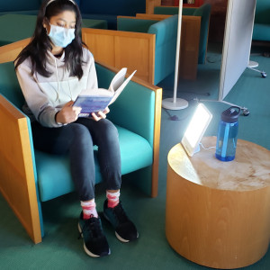 A student reading a book while using a new light therapy lamp.