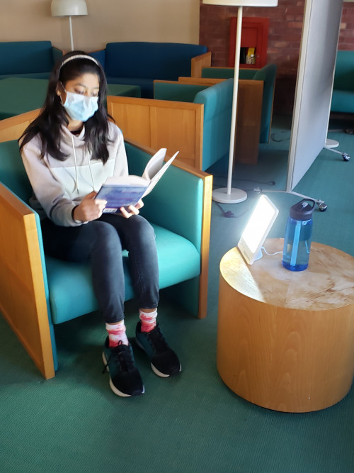 一名学生在使用一种新的光疗灯读书。