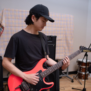Adriel experimenting with an electric guitar in the Maple Tree Recording Studio, summer 2021.