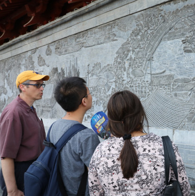 在中国黄河地区，教授和学生在研究一个浮雕板。