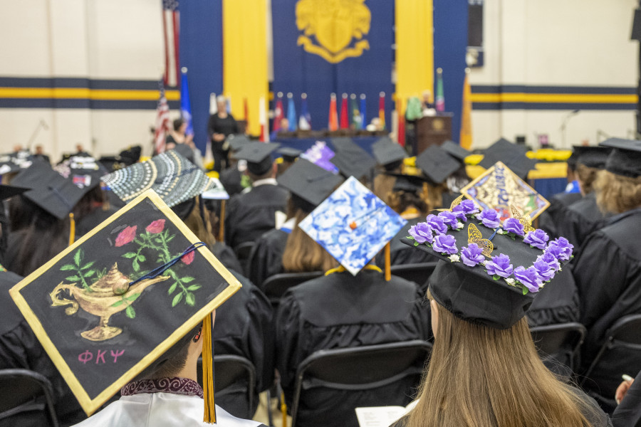 学生们戴着饰有鲜花的帽子观看他们自己的毕业典礼。