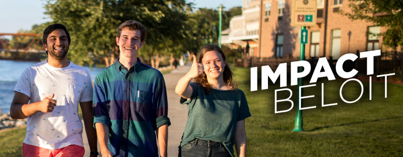 Three students walking along the river walk with the Impact Beloit Logo