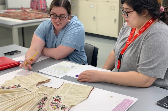 Introduction to Textile Conservation participants conducting a detailed condition report on a Mexican blouse from the Logan Museum's collection.