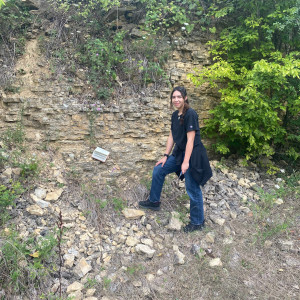 Student poses near limestone wall during field research