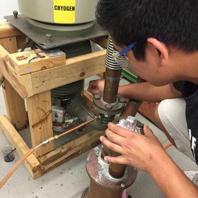 一名学生正在研究粒子加速器的低温管道。