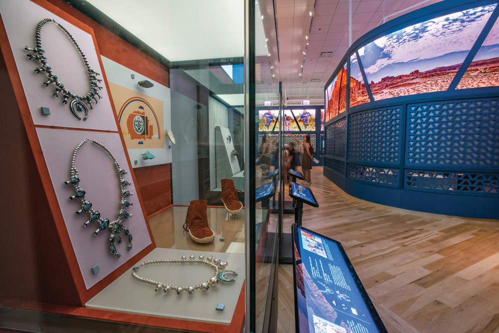 A display case at the Native Truths exhibit showing necklaces, footwear, and other items.