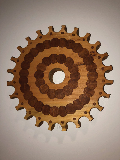 A wooden gear made of interlocking circular pieces of wood of various colors.