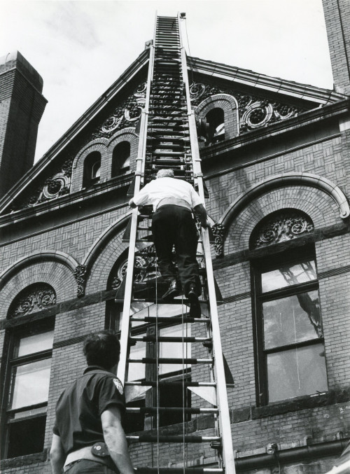 男人们爬上斯科维尔大厅一侧的梯子，向上走向陶俑。